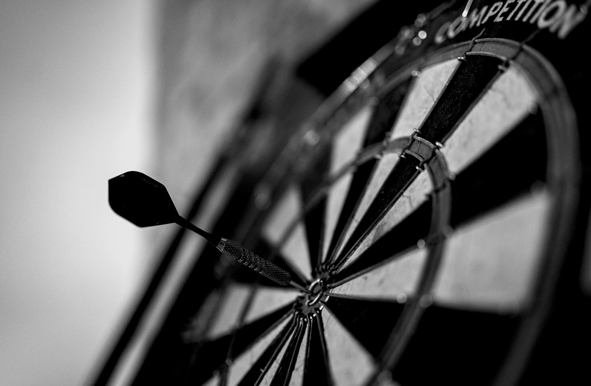 Close-up of a dart hitting the bullseye on a competition dartboard, black and white