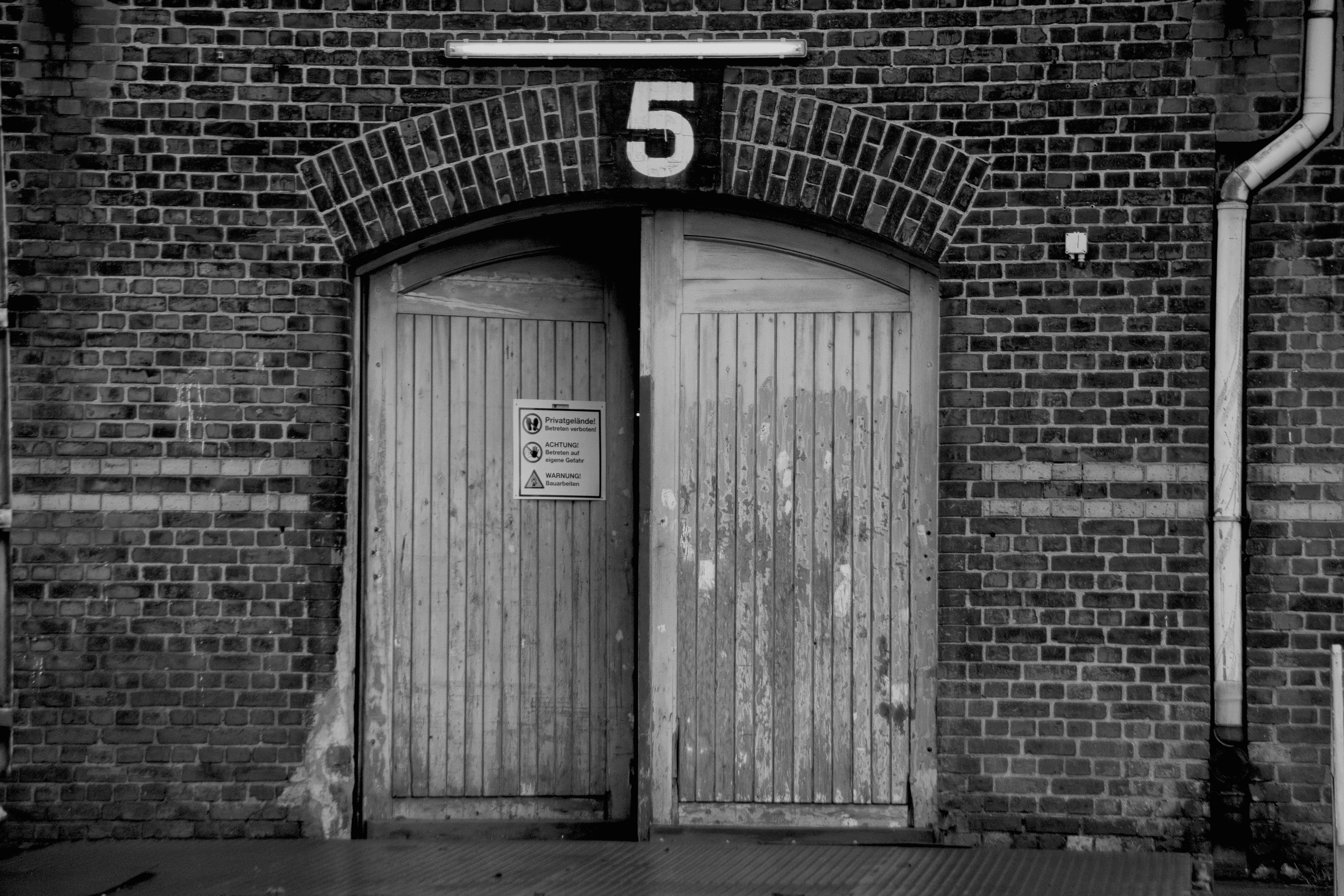 Weathered wooden double door numbered 5 in a brick warehouse wall